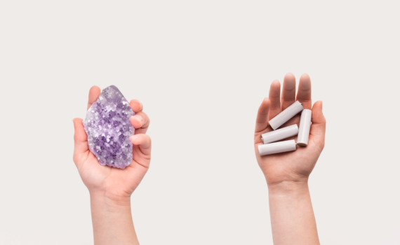 Duas mãos. Uma segurando uma pedra de lítio e outra segurando baterias.