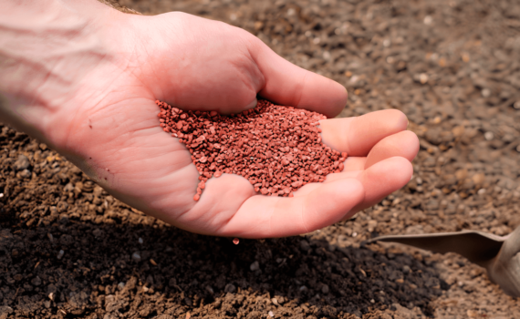 Mãos segurando cloreto de potássio próximo ao chão