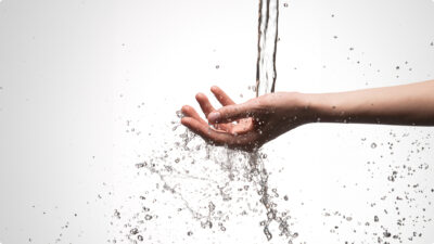 Closeup mão de mulher sob o fluxo de despejo de agua