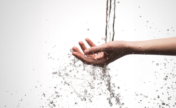 Closeup mão de mulher sob o fluxo de despejo de agua