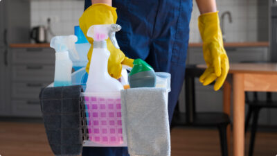 Mulher segurando caixa com produtos de limpeza e agua sanitária