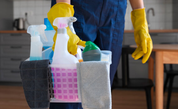 Mulher segurando caixa com produtos de limpeza e agua sanitária