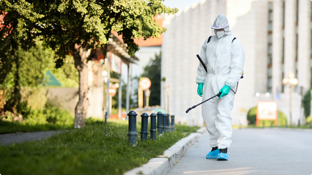 Homem em traje de proteção realizando a esterilização das ruas da cidade